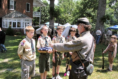 Photo of Boy Scouts joining a Civil war reenactor for a formal ceremony.